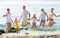 Large family jumping up together on beach on clear summer day