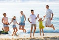 Large family jumping up together on beach on clear summer day