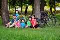 Large family-mom, dad and a group of small children sitting on the grass in Bicycle gear and helmets smiling against the Royalty Free Stock Photo