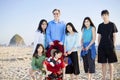 Large family of seven standing beach by ocean