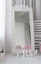 Large fancy carved wooden mirror and candles on the floor in bedroom