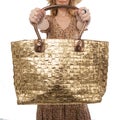 Large female bag of gold color in the hands of a woman in a brown dress isolated on a white background Royalty Free Stock Photo