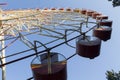 A large Ferris wheel in an amusement park with red and yellow cabins on a blue sky background. Trees in an amusement park Royalty Free Stock Photo