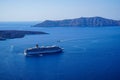 Large ferry ship and speed boats sailing on vast blue mediterranean sea with caldera mountain and sky background
