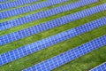 Large field of solar photo voltaic panels system producing renewable clean energy on green grass background