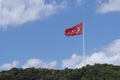 a large flag of Turkey waving on a white flagpole on a hillside with trees on a blue day, copy space Royalty Free Stock Photo