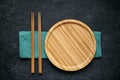 Large flat empty bamboo plate and chopsticks lie on green linen napkin