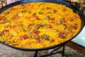 Large flat frying pan with cooked homemade Spanish paella with variety of meats, vegetables, rice, tomato sauce, spices