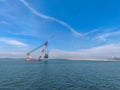 A large floating crane on the ocean near a coastal area. Royalty Free Stock Photo