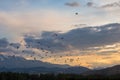 A large flock of birds against the background of the red evening sky at sunset. The paraglider scared off a flock of birds.