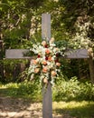 Large flower arrangement hanging on an old wooden cross outside