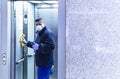 Large format of a male wearing a medical face mask and disinfecting an elevator