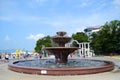 A large fountain in the square in a resort town on a sunny day.