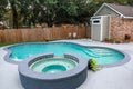 A large free form gray grey accent swimming pool with turquoise blue water in a fenced in backyard in a suburb