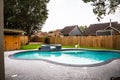 A large free form gray grey accent swimming pool with turquoise blue water in a fenced in backyard in a suburb