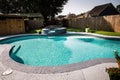 A large free form gray grey accent swimming pool with turquoise blue water in a fenced in backyard in a suburb Royalty Free Stock Photo