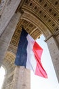 A large french flag fluttering under the Arc de Triomphe in Paris, France