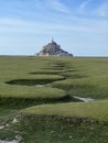 A large french monument Mont Saint Michel behind a huge meadow