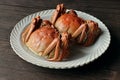 Large, freshly-cooked hairy crabs on a white plate atop a wooden table, ready to be enjoyed