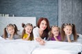 Large friendly family, many children: mom and four pretty cheerful girls triple twins sisters lying on a bed against a gray brick Royalty Free Stock Photo