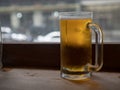 Large frosty beer mug filled with lager sitting on counter top