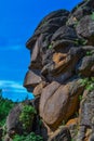 Large geometric red stone rocks form of face profile in light of sun. Krasnoyarsk pillars, nature park in Siberia. Blue sky