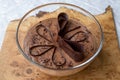 Large glass bowl of chocolate mousse standing on an olive wood platter, decorated with chocolate shavings and curls.