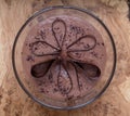 Large glass bowl of chocolate mousse standing on an olive wood platter, decorated with chocolate shavings and curls.