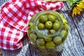 Large glass jar of green pitted olives on tabletop with checked cloth Royalty Free Stock Photo