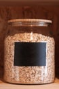 Large glass jar with oats closeup with a black sticker