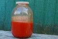 Large glass jar with red tomato juice on a wooden table