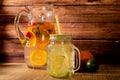 Large glass pitcher with citrus flavored water and homemade lemonade. Glass or jar with drink, lid and straw. Freshness, health