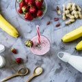 A large glass of strawberry-banana smoothie with ingredients Royalty Free Stock Photo