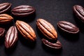 Large glossy chocolate beans on black graphite background.