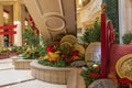 Large gold coins surrounded by lush green plants and colorful flowers and Chinese lanterns and a red arched bridge at The Venetian