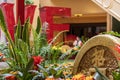 Large gold coins surrounded by lush green plants and colorful flowers and a red arched bridge at The Venetian Resort and Hotel