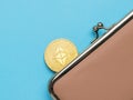 A large gold digital coin sticking out of the wallet on a blue background
