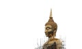 A large golden Buddha image undergoing renovations located outdoors in a Thai temple.  Isolated white background Royalty Free Stock Photo