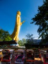 Large golden Buddha in the middle of the market, sunny blue sky.
