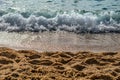 Large-grain sand against the backdrop of a sea wave on the Kleopatra beach in Alanya Turkey, close-up. Natural tropical beach