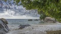 Large granite boulders are scattered in the surf on a tropical beach. Royalty Free Stock Photo