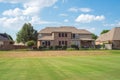 Large grassy and rolling lawn of suburban park next to upscale residential neighborhood row of two-story houses in Flower Mound,