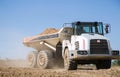 Large gray articulated dumper at a construction site drives down a dusty road