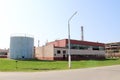 A large gray metal container, a barrel with an open hatch and a red production building at an oil refinery, petrochemical, chemica