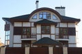 Large gray private house with brown windows and a tiled roof with chimneys