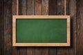 Large green blackboard hanging on ropes with wood planks background