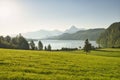 A large green field with a lake and mountains in the background Royalty Free Stock Photo