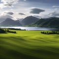 large green field with a lake and mountains in the background Royalty Free Stock Photo