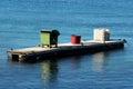 Large green plastic trash container next to big plastic barrel and white IBC plastic tank on top of elongated floating pier Royalty Free Stock Photo