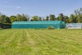 Large green poly-tunnel and small greenhouse at the end of a large lawn Royalty Free Stock Photo